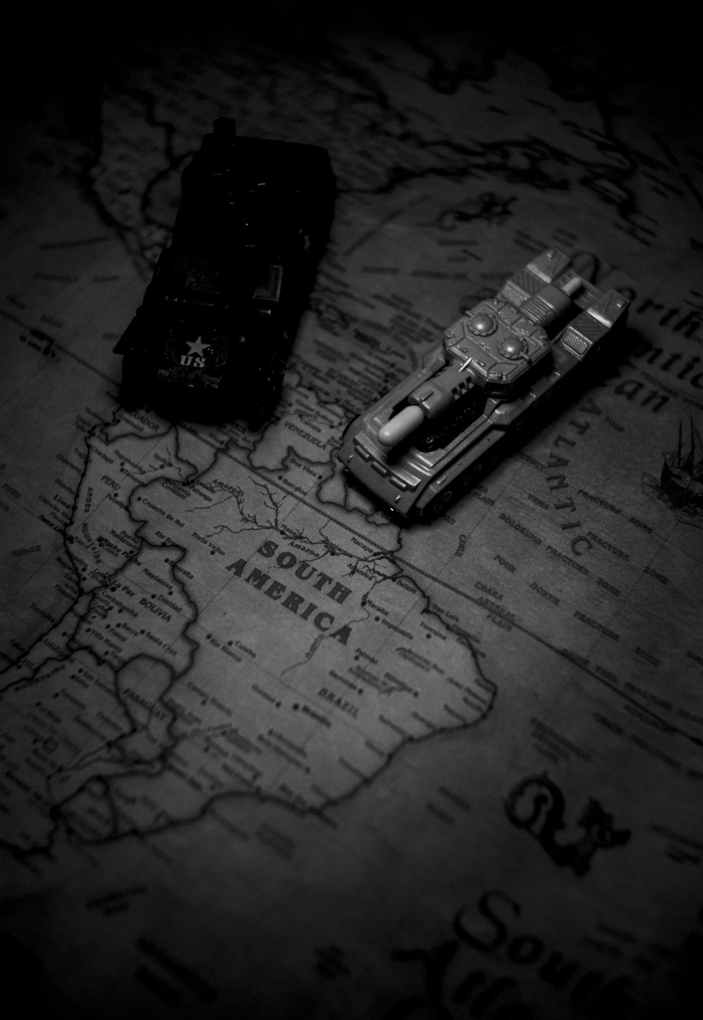 Close-up of toy tanks on a vintage world map, focusing on South America.